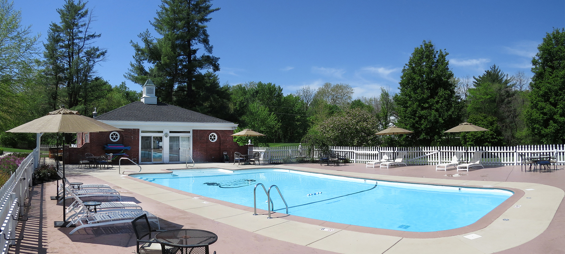 A swimming pool with red brick pool house in the background