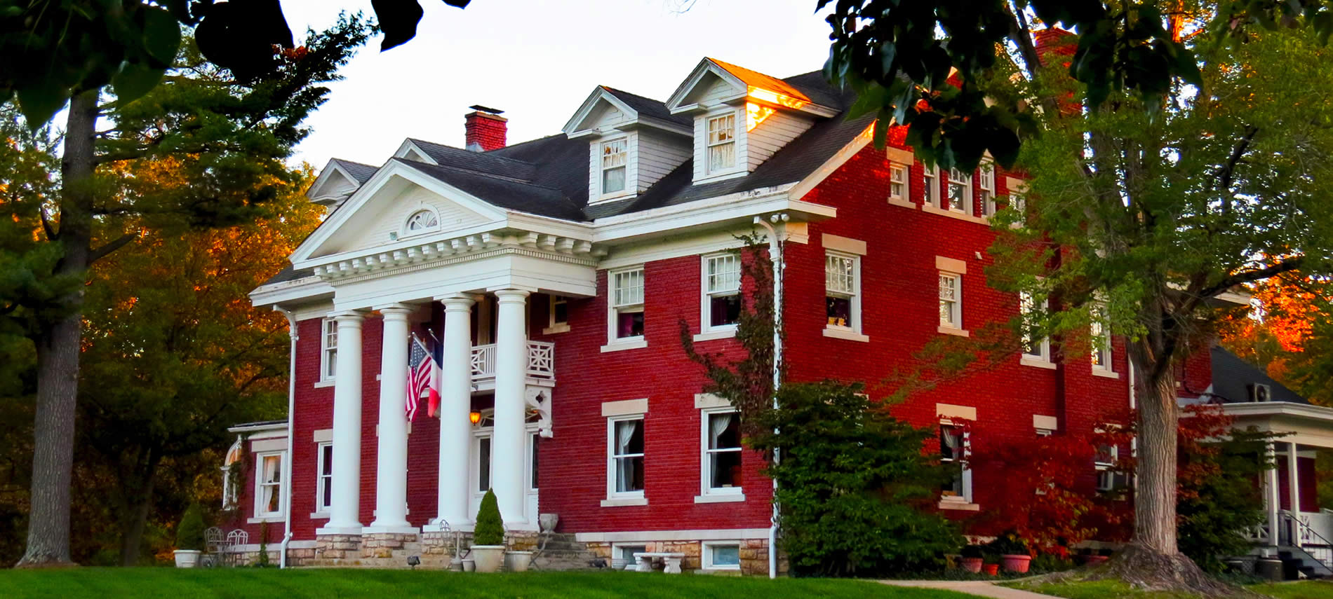 A red brick Georgian colonial mansion with four white columns standing two stories tall