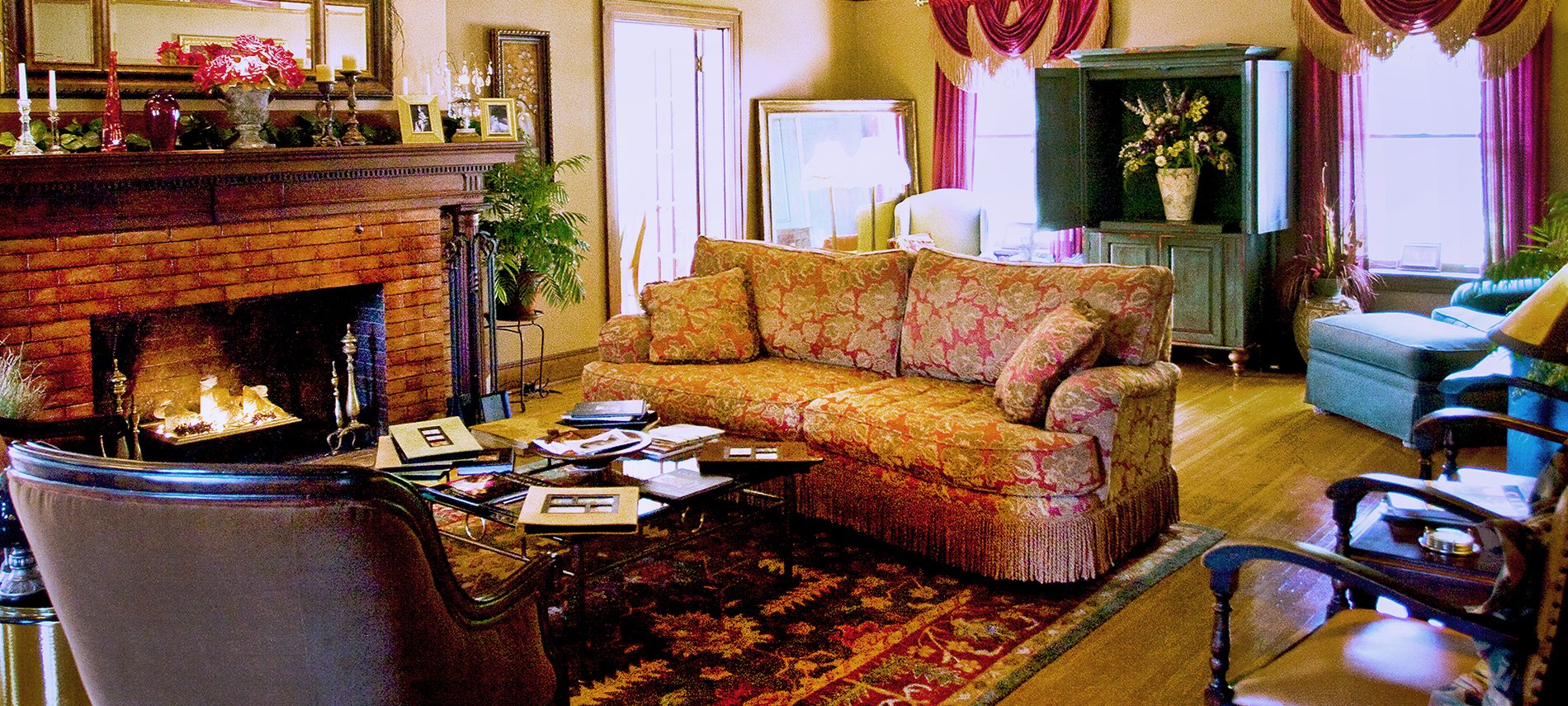 A living room with an overstuffed burnt orange sofa to the right and a brown brick fireplace to the left