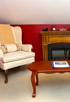 A white wingback chair and coffee table in front of an electric fireplace