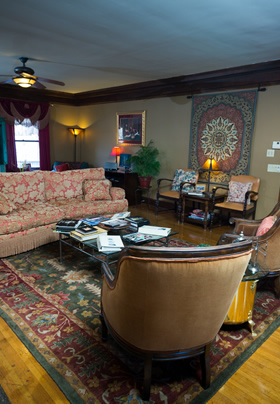 Two lounge chairs and an album-filled coffee table in front of a burnt orange sofa on a tapestry rug