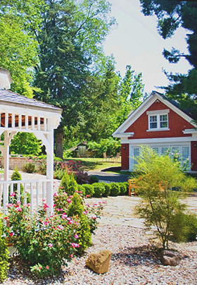 A white gazebo to the left and a red brick cottage in the distance to the right